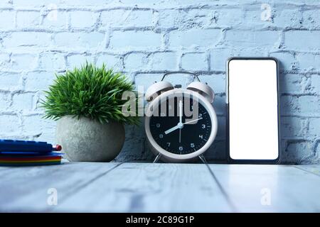 alarm clock, notepad and smart phone with empty screen on table  Stock Photo