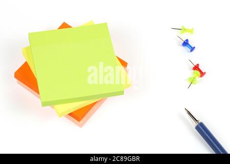 colorful adhesive notes with pins and pen on white surface Stock Photo