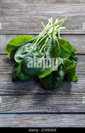 bunch of green fresh spinach leaves on old gray wooden table Stock Photo