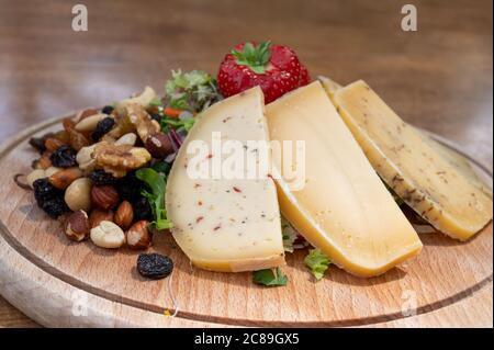 Tasting wooden board with different types of Belgian hard abbey cheeses, nuts and fruits close up Stock Photo