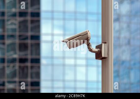 video surveillance security camera against glass office facade background Stock Photo