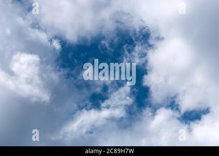 blue sky clearing gap in white dramatic clouds lit by the sun Stock Photo