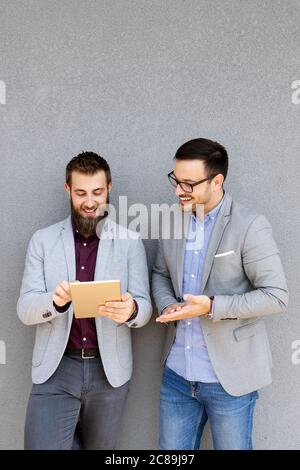 Positive successful business specialists discussing plan while digital tablet outdoors. Stock Photo