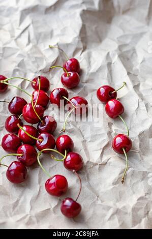 Berries of ripe cherries on a background of craft paper. Selective focus. Vertical crop. Copy space. Top view. Stock Photo