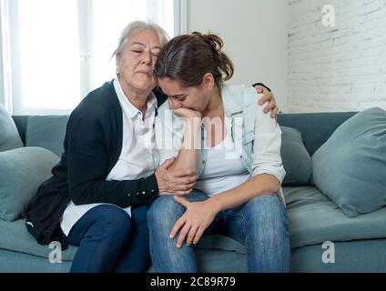 Senior mother comforting adult daughter grieving loss of loved one fighting the Coronavirus. Elderly mother embracing adult daughter suffering from de Stock Photo