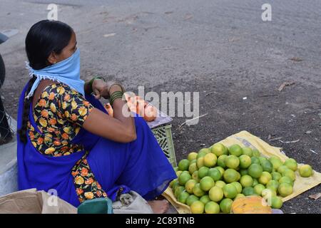 Hyderabad, Telangana, India. july-20-2020: woman, fruits trader was wearing mask in her work, women selling fruits at road side, small business Stock Photo