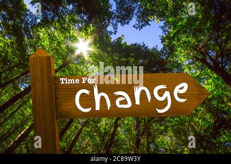 Singpost with the Words Time For Change in the Middle of a Forest backlit by the Sun Stock Photo