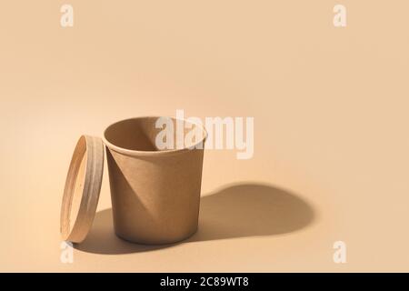 Craft paper soup cup with shadow on brown paper background. Empty container. Stock Photo
