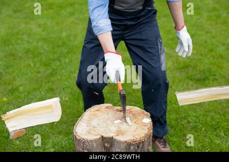 Adult man is chopping wood with axe. Close-up of two flying pieces of wood. Stock Photo