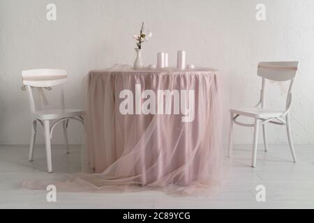 Two white chairs and covered table with pink table clothes Stock Photo