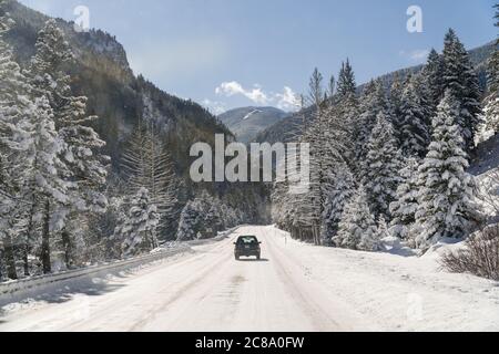 View out of car windshield of car on snow-covered mountain road Stock Photo