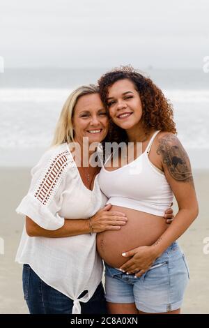 Mom Posing with Pregnant Daughter on Beach Stock Photo - Alamy