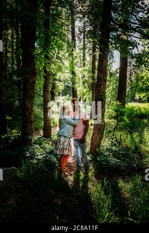 Biracial couple standing and laughing in forest Stock Photo