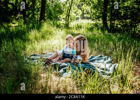 Sister kissing infant brother outside in tall grass Stock Photo