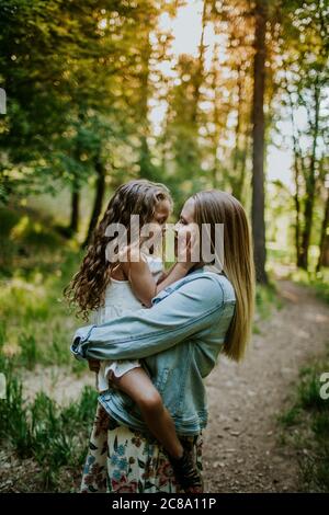 Happy mother holding young girl in forest Stock Photo