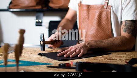 craftsman working with hands and hammer on leather Stock Photo
