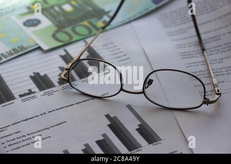 100 Euro banknote, glasses, pen and financial diagrams report. business concept Stock Photo