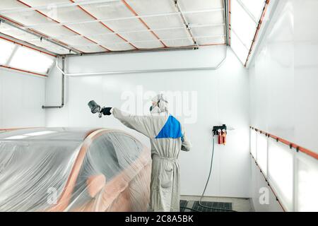 repairman painter in chamber painting automobile car roof Stock Photo