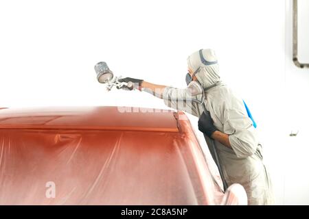 Car body painter spraying paint in garage or workshop with airbrush Stock Photo