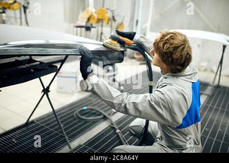 Auto mechanic grinds car part for painting. Car body work auto repair paint after accident Stock Photo