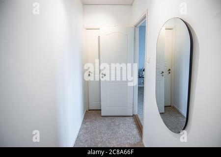 A white painted hall in an apartment. Two doors and a mirror. Stock Photo