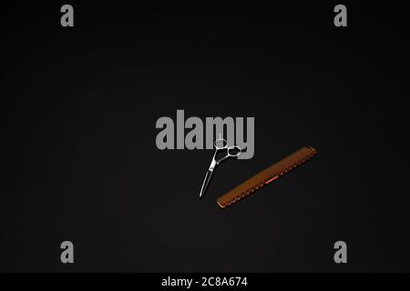 Hair cutting shears and comb isolated on black background Stock Photo