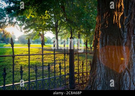 Long shadows through wrought iron fence surrounding La Fayette Park with lens flare  effect at sunset  St Louis Missouri USA Stock Photo