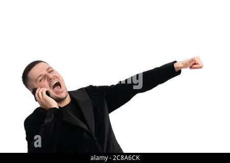 Positive confident happy young male manager in dark blue suit standing against isolated background and gesturing hand while communicating on mobile Stock Photo