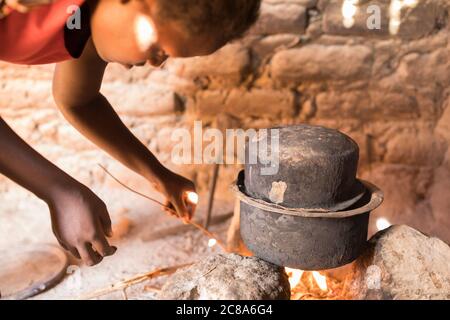 Mary Muinde (20), Regina Mwangangi's daughter-in-law, cooks on an open fire in their family's home in Makueni County, Kenya. LWR Isaiah 58 Project - Stock Photo