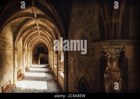 Detail of the medieval gothic cloisters of the cathedral of Evora, main city of the Alentejo region (Portugal) with an evangelist statue holding the b Stock Photo