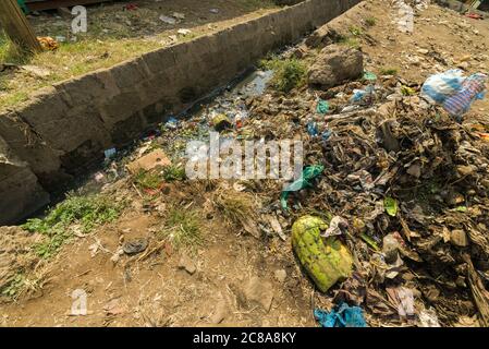 An open sewer filled with rubbish by the side of a dirt alley, Korogocho slum, Kenya, East Africa Stock Photo