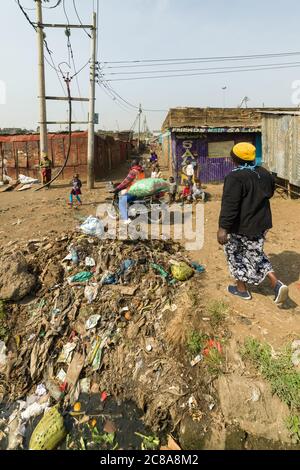 An open sewer filled with rubbish by the side of a dirt alley, Korogocho slum, Kenya, East Africa Stock Photo