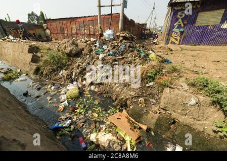 An open sewer filled with rubbish by the side of a dirt alley, Korogocho slum, Kenya, East Africa Stock Photo