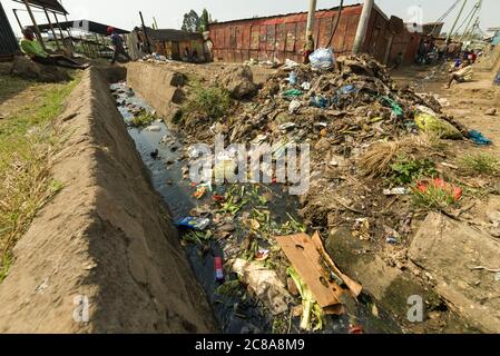 An open sewer filled with rubbish by the side of a dirt alley, Korogocho slum, Kenya, East Africa Stock Photo