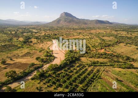 Nzaui rock rises above farmland, orchards and seasonal rivers in Makueni County, Kenya, East Africa. Stock Photo