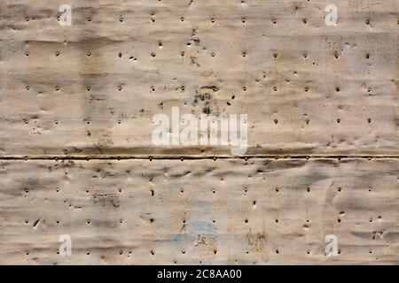 Old stained, beaten and rusty metal panel in a door with nails in rows. Image for backgrounds or designs Stock Photo