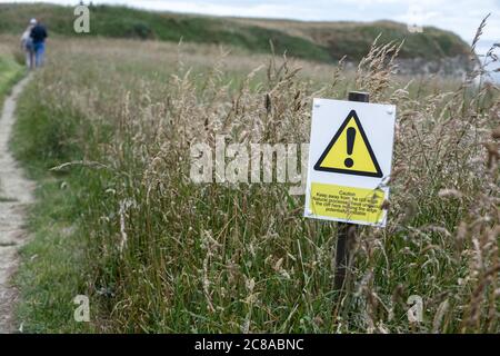 Warning sign on the footpath at Bempton cliffs warning of unstable cliff edge. Stock Photo