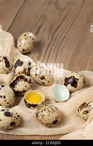 Composition of several quail eggs on decorative fabric on a wooden table close-up, copy space, virtical banner, flatlay Stock Photo