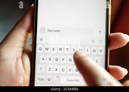 Closeup shot of a person texting the message 'stay home' on a smartphone Stock Photo