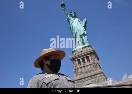 Liberty Park Ranger Alexander Parody speaks with a visitor in front of the the Statue of Liberty, now that Liberty Island is open to visitors as part of New York City's Phase 4 reopening, but access to the Statue of Liberty itself, including crown and pedestal, remains closed due to COVID-19 restrictions, New York, NY, July 22, 2020. Since opening on Monday, the usual crowds of tens of thousands of people have been absent, instead a slow stream of only a few hundred tourists have been counted visiting “Lady Liberty”. (Anthony Behar/Sipa USA) Stock Photo