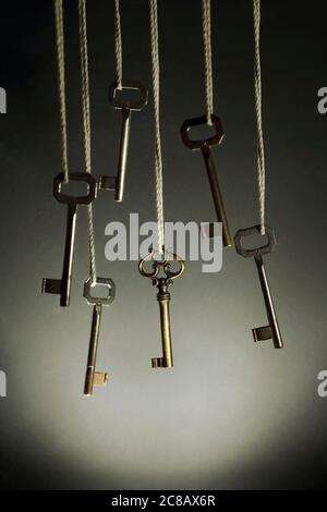 series of keys haging agianst black, focus is on one different retro key Stock Photo