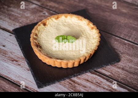 A top view of a delicious tart with mint on top on a black stone plate Stock Photo