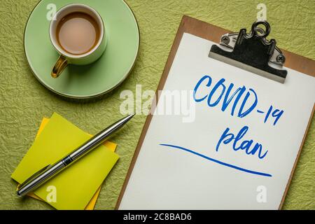covid-19 plan, handwriting on a clipboard with coffee - coronavirus pandemic business concept Stock Photo