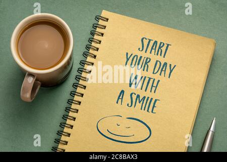 start your day with a smile inspirational note - handwriting in a sketchbook with a cup of coffee, lifestyle, business and positivity concept Stock Photo