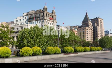Shanghai, China - April 17, 2018: View on AIA building and Sassoon House (Fairmont Peace Hotel). Empty promenade of The Bund in the foreground. Stock Photo