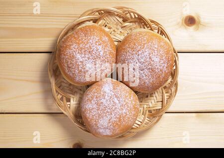 Three sweet donuts in wicker plate on wooden table, top view Stock Photo
