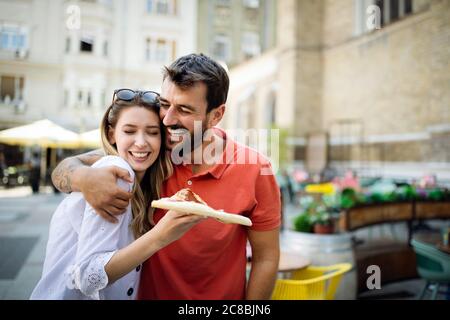 Happy couple laughing and eating pizza, having fun together Stock Photo