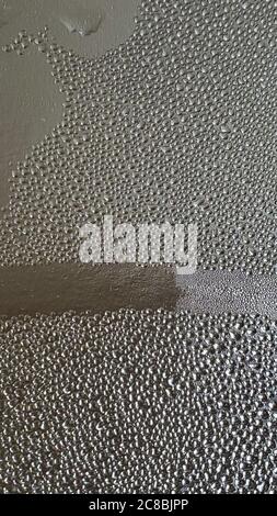 Wet patterned texture of clear water bubbles on reflective foil. Abstract background with drop condensation on reflective silver shiny surface Stock Photo