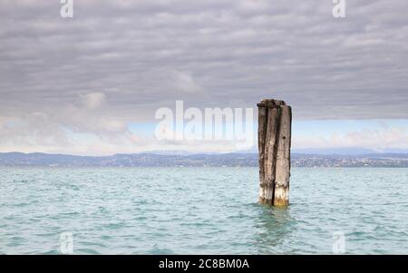 The view past a mooring post on the Sirmione waterfront.  Sirmione is a resort town on the edge of Lake Garda in North East Italy. Stock Photo