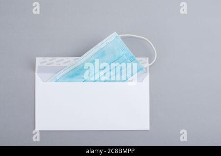 Surgical mask inside a white envelope in the gray background. Stock Photo